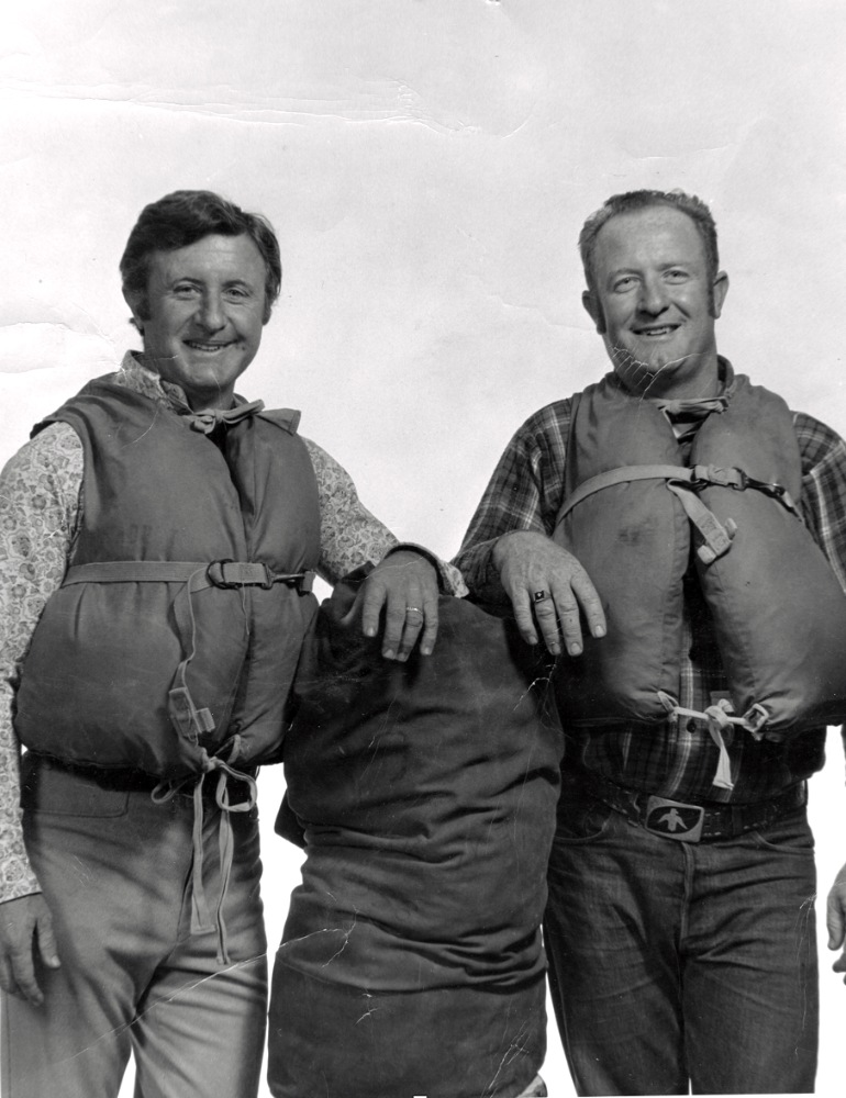 black and white photo of Don and Ted Hatch posing for photo with life vests and river bag in the 1970s - Hatch family history