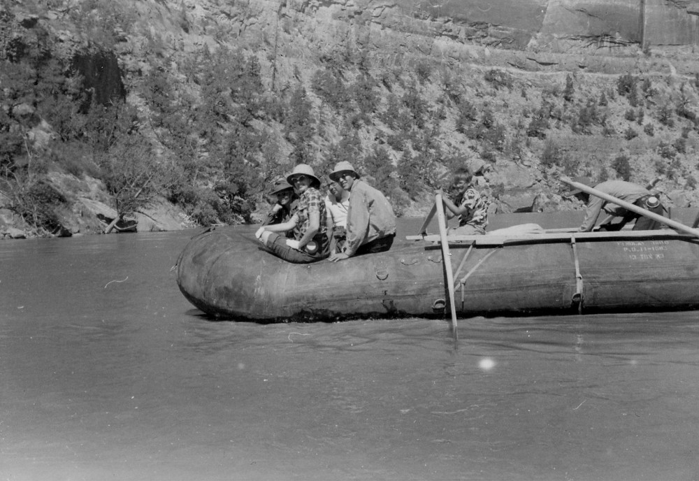 People in the 1950s riding a river rafting rig made of repurposed military surplus pontoons