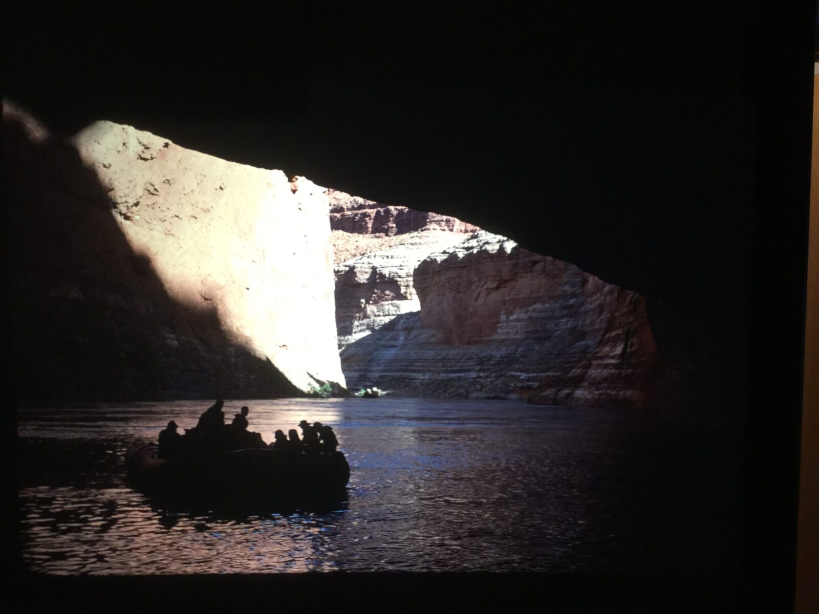 A boat entering Redwall Cavern. This large limestone cave is normally a fun place for river trips to stop and play as its interior is filled with an enormous sandy beach.