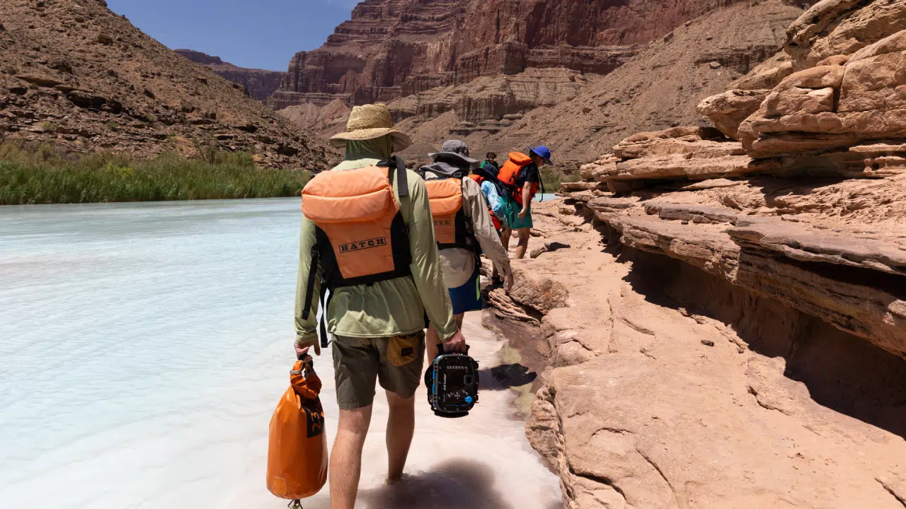 People hiking by beautiful blue waters of Colorado River on Grand Canyon trip with Hatch River Expeditions