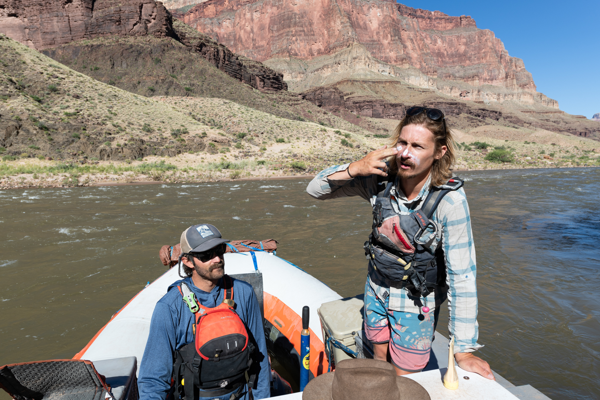 a river guide demonstrates how to appropriately apply sunscreen to his face while on a raft on a sunny day in Grand Canyon