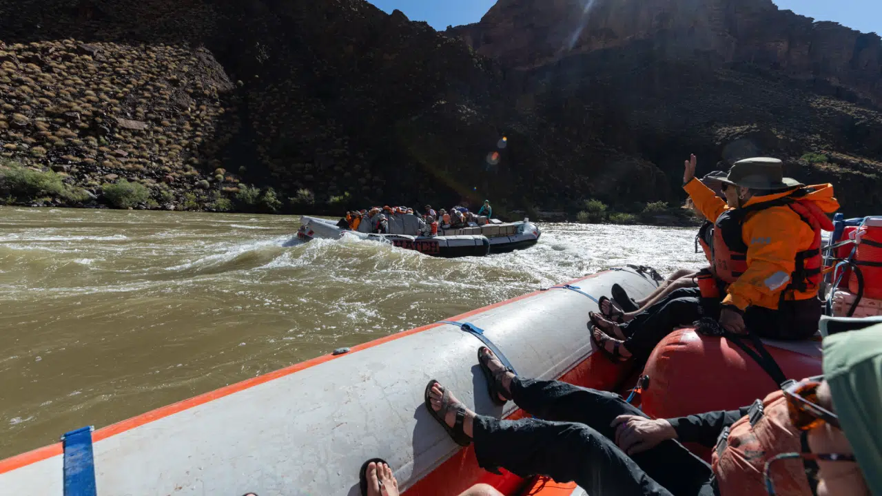 People on boat waving on 7 day lower grand canyon hiking trip on colorado river