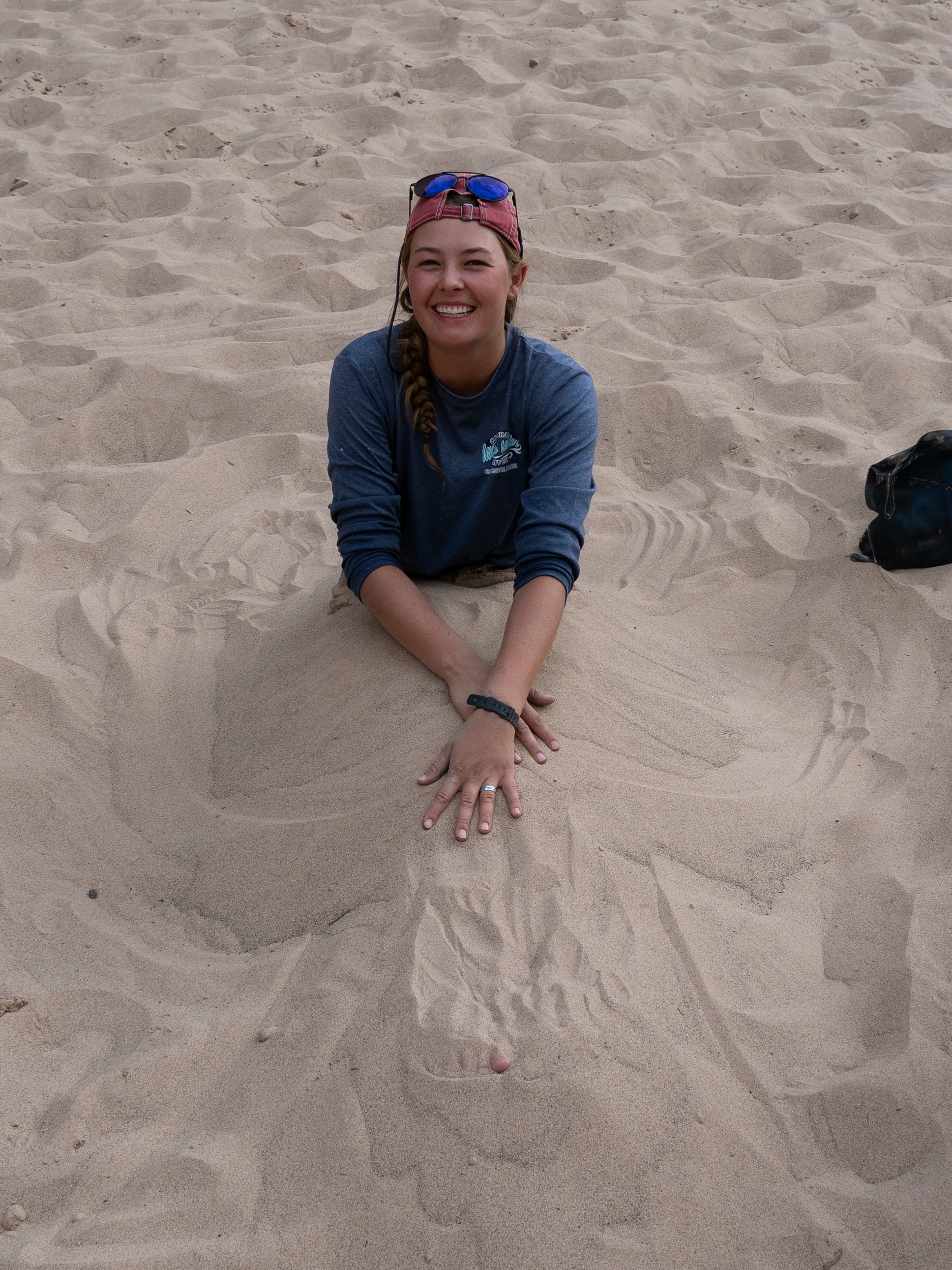 Smiling guest buried in sand on a Grand Canyon rafting trip. Photo credit: Amy Horn. 