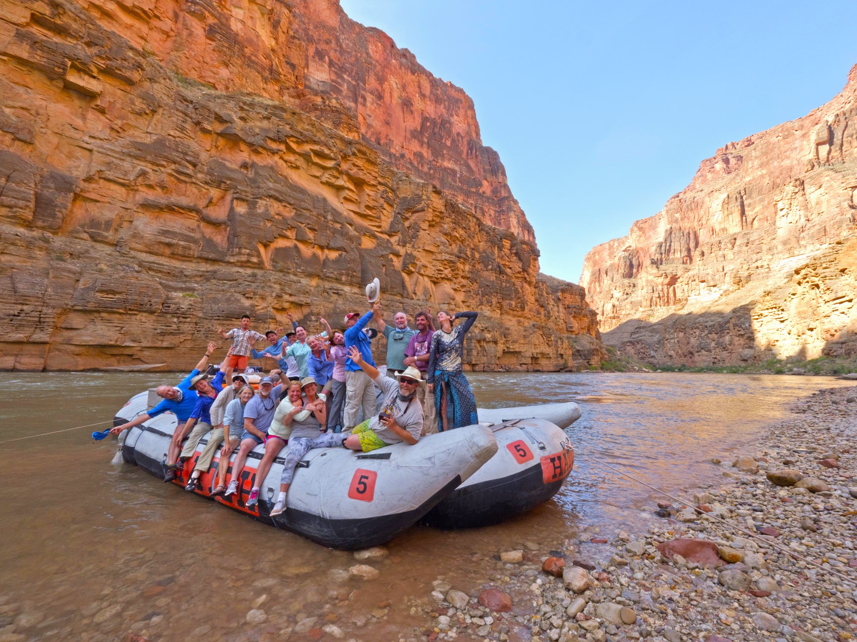 Happy people on a river rafting trip with Hatch River Expeditions pose on raft in Grand Canyon