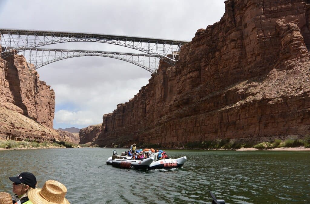 A recent photo of the two Navajo Bridges from the river with a Hatch boat below.