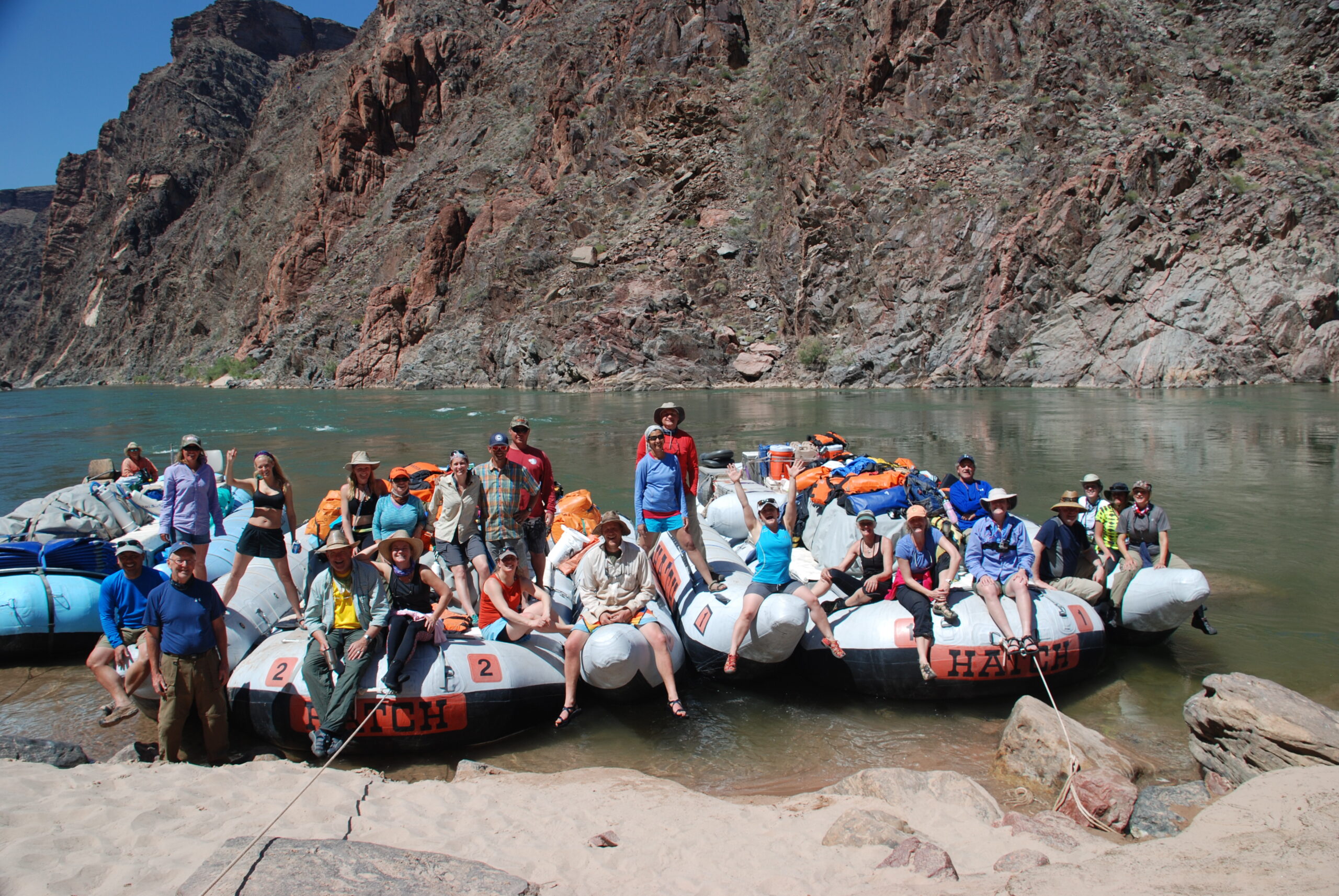 A group of Hatch charter guests posing for a photo on the Hatch rafts during their private Grand Canyon trip. Photo credit: Morris Outwater.