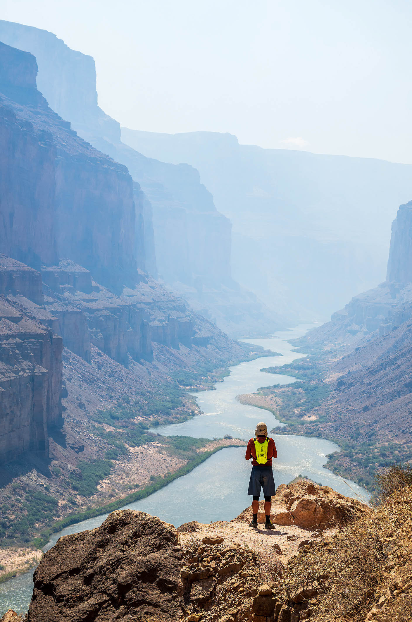 A Hatch guests stands on at the edge of the Grand Canyon on the trail to the Nankoweap Granaries, looking down at the Colorado River. Photo credit: Michael Neumann.