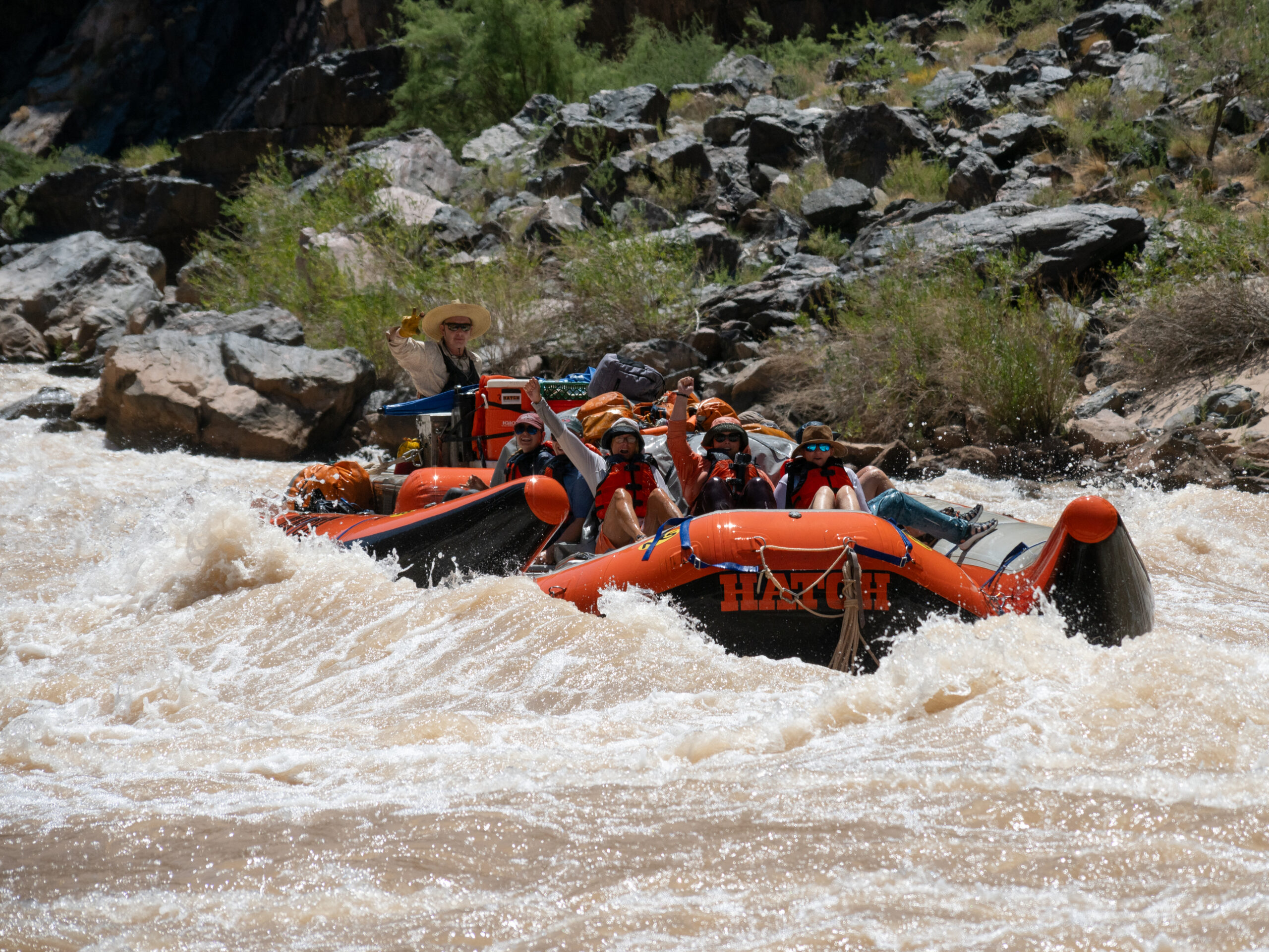 Hatch guests in an orange raft running a rapid on the Colorado River