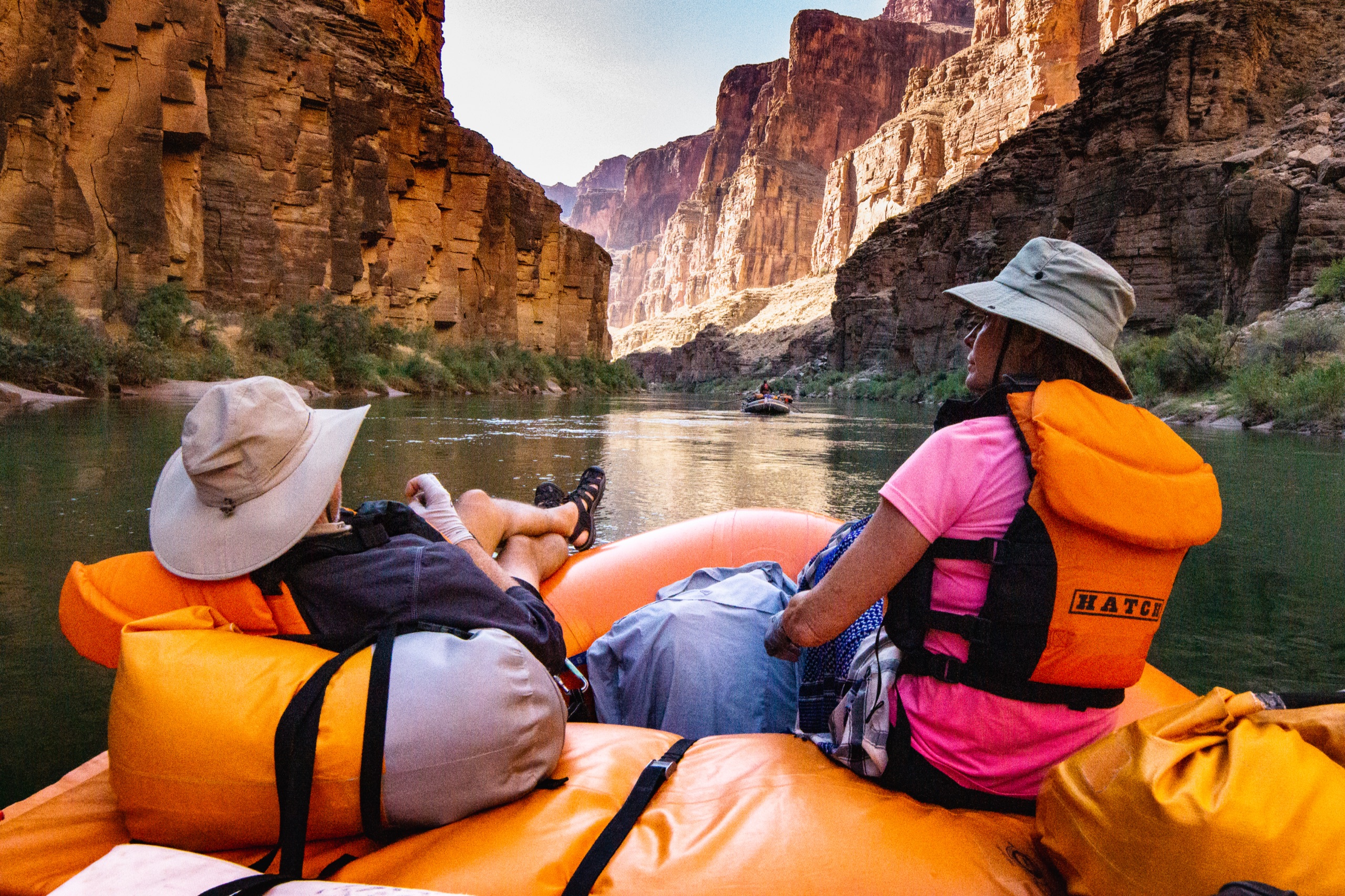 Hatch guests riding an orange oar raft between the red walls of the Grand Canyon